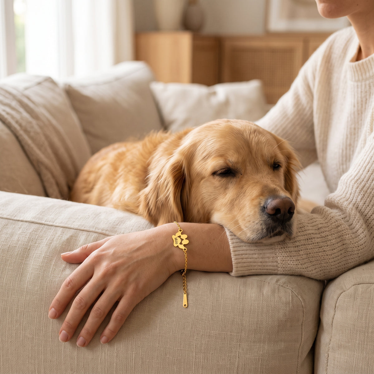 Golden retriever posant sa tête sur le bras d'une femme qui porte le bracelet patte en or