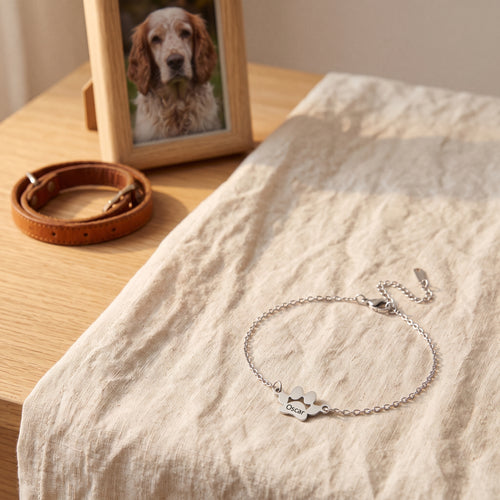 Bracelet souvenir en argent gravé Oscar, posé devant la photo d'un chien et son collier